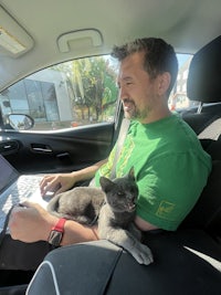 a man sitting in the back seat of a car with a cat